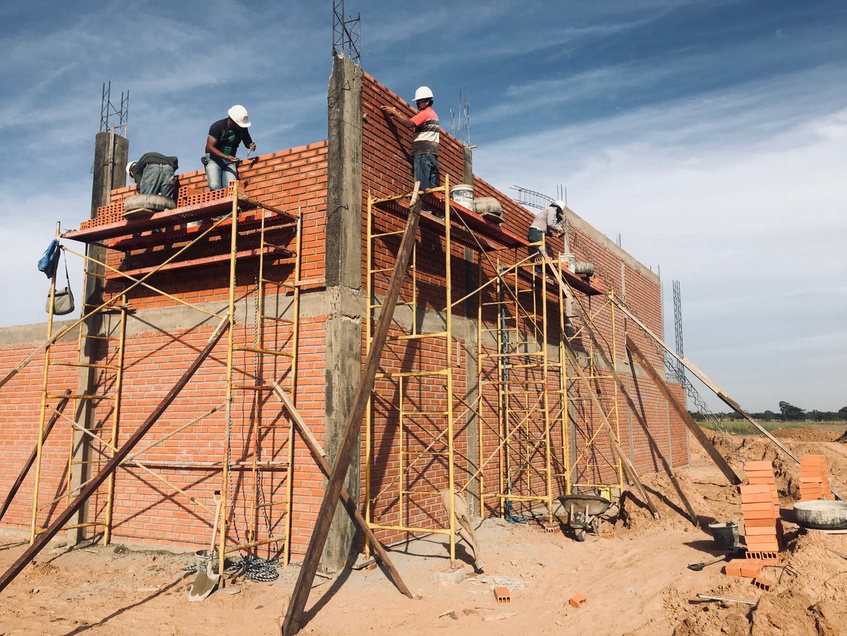 Albañiles levantando muros de ladrillo en vivienda